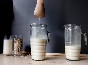 Straining homemade Almond Milk in Glass Bottles