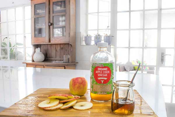 apple cider vinegar on board with cut apple slices